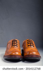 Male Footwear Ideas. Full Broggued Tan Leather Oxfords Broggued Shoes Against Gray  Background. Vertical Image Orientation