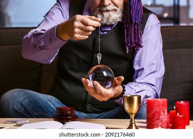 Male Fortune Teller With Crystal Ball And Pendulum At Home