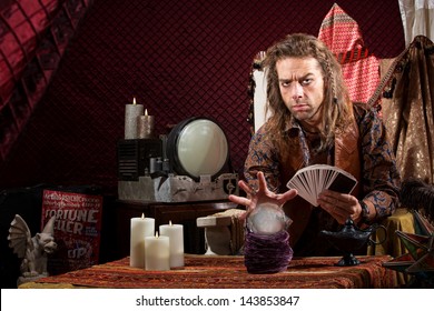 Male Fortune Teller With Tarot Cards Waving Hand Over Crystal Ball