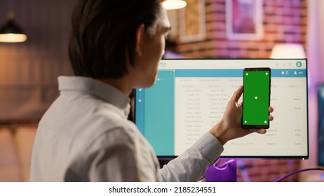 Male Freelancer Holding Smartphone With Greenscreen On Display. Looking At Isolated Copyspace Background With Blank Chroma Key And Mockup Template On Mobile Phone Touchscreen.