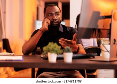 Male freelancer using mobile phone to call manager at job, talking on phone line to do research project with data report and documents. Having remote discussion with smartphone during sunset. - Shutterstock ID 2174911709