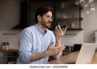 Male freelancer work from home having conversation with colleague client remotely by phonecall, sit in domestic kitchen hold smartphone answer phone call on speakerphone, modern tech lifestyle concept - Powered by Shutterstock - Get 15% off with code: PIKWIZARD15