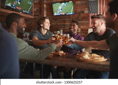 Male Friends Drinking Beer And Eating Burgers In Sports Bar