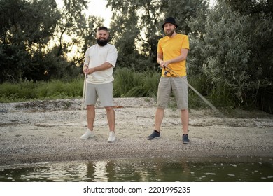 Male Friends Fishing At Sunset On Lake. Leisure And People Concept