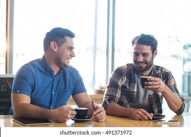 Male Friends Interacting While Having A Cup Of Coffee In Caf\x92\xA9