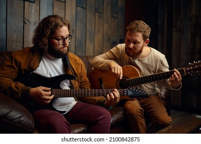 Male friends playing guitar at home together