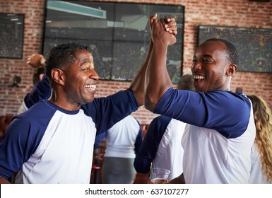 Male Friends Watching Game In Sports Bar Celebrating