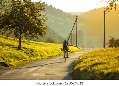 Male fully equipped cyclist riding a bike during sunset on the empty road in rural Germany. - Shutterstock ID 1250674513