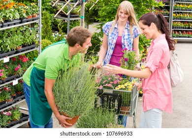 Male Garden Centre Worker Selling Potted Plant To Female Customers