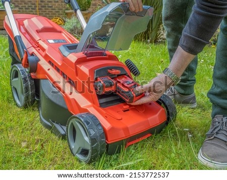 Male Gardener changing the Lithium Ion battery on a electric cordless lawnmower