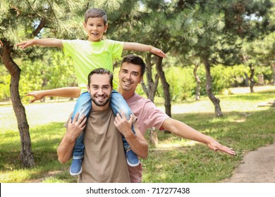 Male Gay Couple With Foster Son Having Fun In Park. Adoption Concept