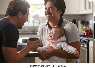 Male Gay Couple Holding Baby Girl In Their Kitchen