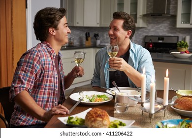 Male Gay Couple Making A Toast At Dinner In Their Kitchen