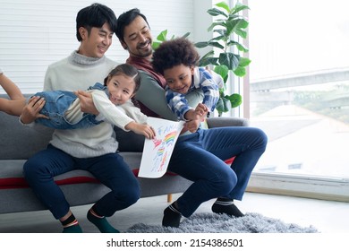 Male gay couple show their kid's family drawing, gay couple having fun with kids at home, LGBTQ family concept - Powered by Shutterstock