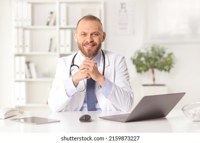 Male General Practitioner Sitting In An Office And Smiling At Camera