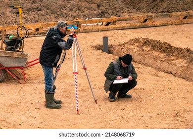 A male geodetic engineer is surveying a land plot for the correct placement of a residential building. Checkpoint check . - Shutterstock ID 2148068719