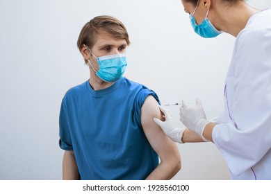 Male Getting Covid-19 Vaccine. Close Up Doctor Making Injection To Patient In Medical Mask. Syringe Of Coronavirus Vaccine. Man Receives Jab Vaccinated. Pacents Gets A Flu Shot. Inject In Arm