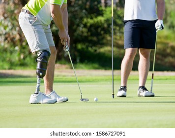 Male Golfer With Artificial Leg On Course Putting Ball On Green