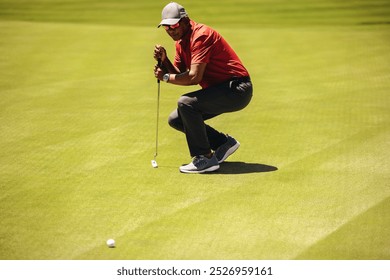 Male golfer leaning on a putter on the green, focusing intently on aligning a crucial golf ball shot. Professional golf player strategising his next shot. - Powered by Shutterstock