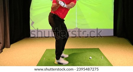 Male golfer makes swing golf club indoors. Golf simulator and training on a virtual golf course