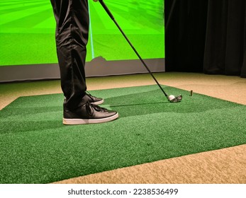 Male golfer plays golf indoors on golf simulator closeup. Driving range with screen - Shutterstock ID 2238536499