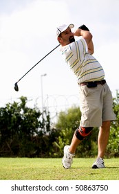 Male Golfer Teeing Off With A Injured Knee Wearing A Knee Brace.