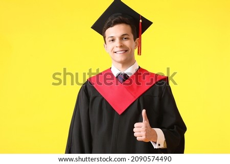 Male graduating student showing thumb-up on color background