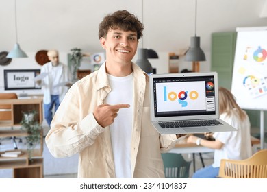 Male graphic designer pointing at laptop in office - Powered by Shutterstock