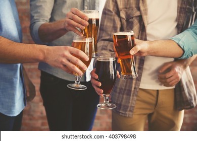 Male group clinking glasses of dark and light beer on brick wall background - Powered by Shutterstock