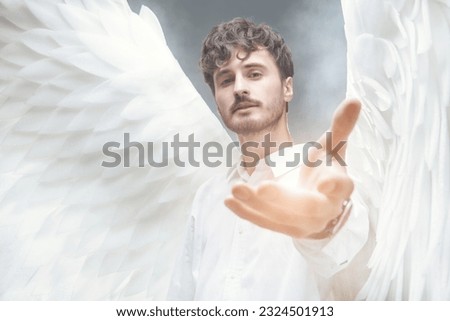 The male guardian angel holds out his hand to the camera with calm and hope in his eyes. Heavenly light and white haze surround him.