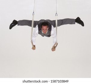 Male Gymnast In Business Suit, On The Still Rings