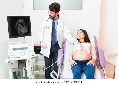 Male gynecologist doing an ultrasound on a pregnant woman. Excited pregnant woman looking at the sonogram of her baby in the machine 