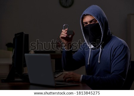 Male hacker hacking security firewall late in office