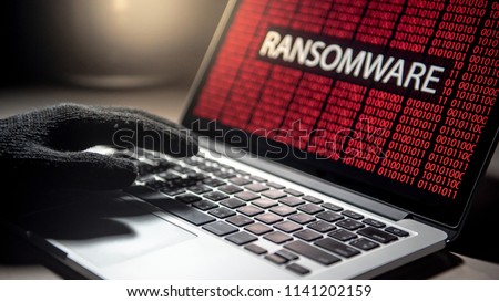 Male hacker hand on laptop computer keyboard with red binary screen of ransomware attacking. Cyber attack and Internet data security concept