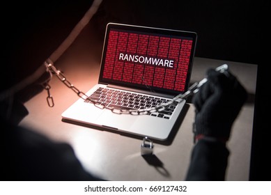 Male hacker locking computer by using chain and padlock, malware ransomware Trojan concept. Internet security concept