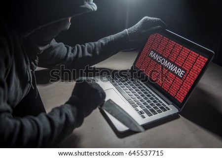 Male hacker threading computer laptop with knife showing on screen with ransomware warning, internet security system concept