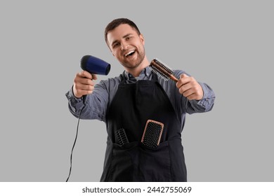 Male hairdresser with dryer and brush on light background - Powered by Shutterstock