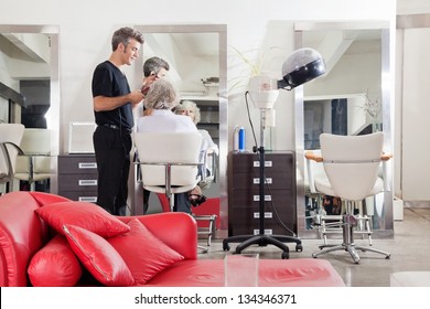 Male hairstylist straightening client's hair at beauty salon - Powered by Shutterstock