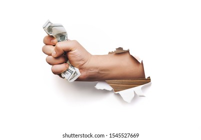 A male hand appears in the hole in torn white paper and squeezes two hundred-dollar bills. The concept of poverty, benefits, scholarships, and stinginess. Isolated.