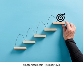 Male hand arranges a wooden block staircase with target icon. Achieving goals and objectives or goal setting concept. - Shutterstock ID 2188034873
