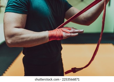 A male hand of boxer or fighter with red boxing bandages before the fight or training in sport gym. - Powered by Shutterstock