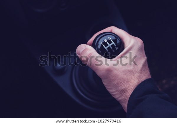 Male hand changing gear in the\
car while driving the motor vehicle, ultra violet toned\
shadows