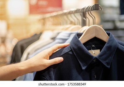 Male Hand Choosing Clothes For Checked Pattern Cotton Polo Shirt On The Rack In Cloth Shop At Department Store. Check Price, Discount And Promotion Of Clothing Product.