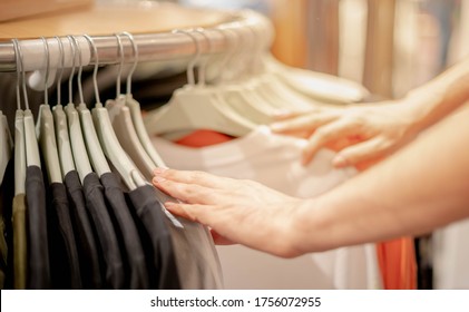 Male hand choosing clothes for checked pattern cotton dress on the rack in cloth shop at cloth shop department store. Check price, discount and promotion of clothing product. - Shutterstock ID 1756072955
