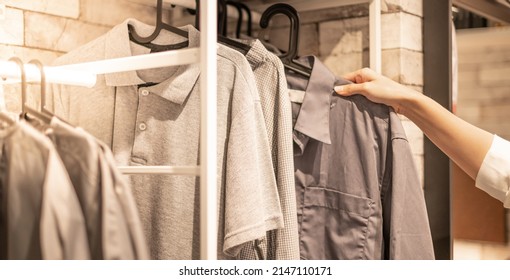 Male Hand Choosing Clothes For Checked Pattern Cotton Polo Shirt On The Rack In Cloth Shop At A Department Store. Check Price, Discount, And Promotion Of Clothing Products.