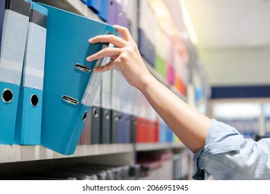 Male Hand Choosing New Light Blue Ring Binder File Folder From Colorful Shelf Display In Stationery Shop. Buying Office Supplies Concept