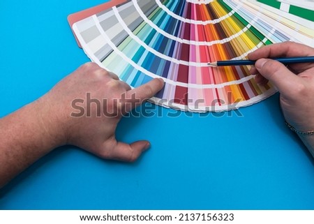 male hand choosing paint tone at color sampler isolated on blue background.  different colors 