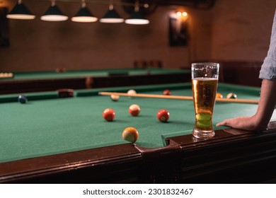 Male hand, colorful billiard balls and pool stick on pool table with glass of beer. Billiard sport concept. - Powered by Shutterstock