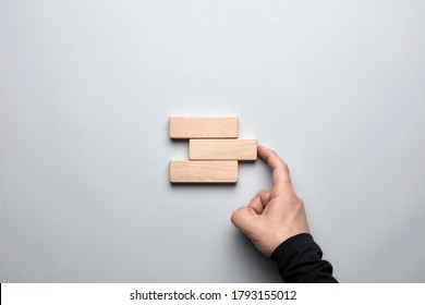 Male hand completing the gap between the wooden blocks. Concept of to accomplish a goal or to find a solution in business.