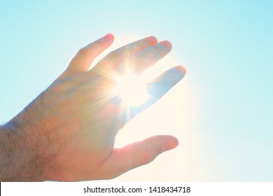 Male hand covers the sun. The sun's rays shine through the hand. Close-up. Background. Texture. - Powered by Shutterstock